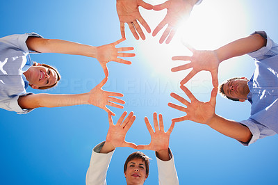 Hands placed in a circle over sky as the background