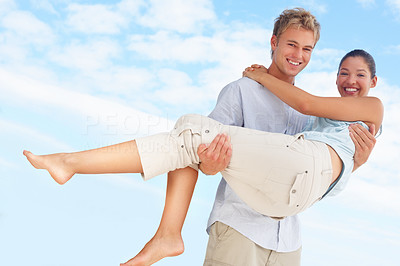 A handsome young man carrying his pretty girlfriend with blue sky as the background