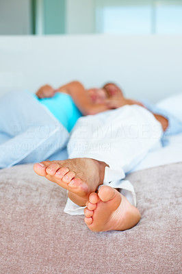 Couple lying on bed with focus on males feet
