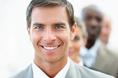 Closeup of a happy young business man with his colleagues at his back