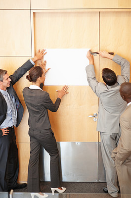 Business colleagues putting up a white paper on their office wall