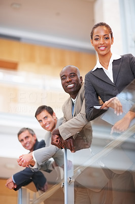 Confident business colleagues resting on a glass railing