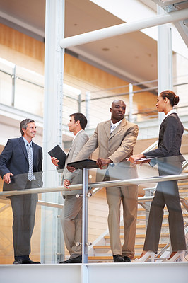 Successful business group standing by a glass railing