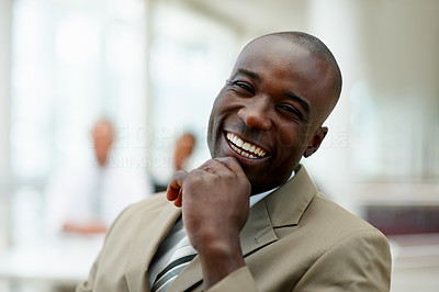 A delighted African American business man laughing with hand on the chin