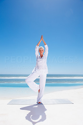 Full length image of an old woman practicing yoga at the beach