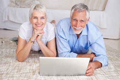 Happy senior couple lying down with a laptop