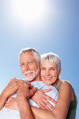 An old woman with her arms around her husband, outdoors