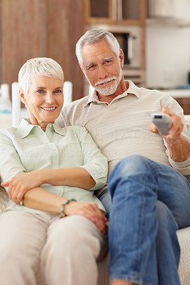 A senior old couple spending time by watching television
