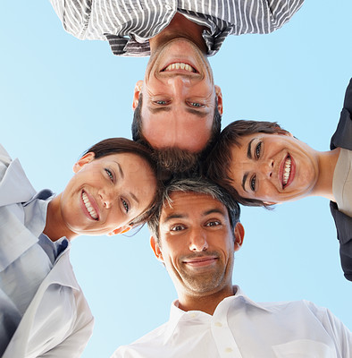Upward view of a group of happy business colleagues with their heads together