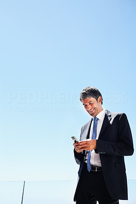 Portrait of a business man messaging on a mobile with blue sky as the background