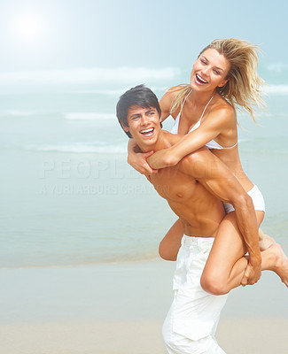 Handsome young man carrying his cute young girlfriend on his back at a beach