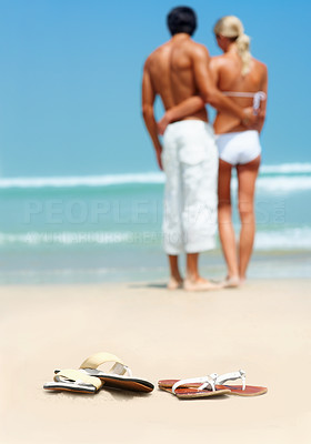 Rear view of a young couple standing together on the beach with their scandals left behind