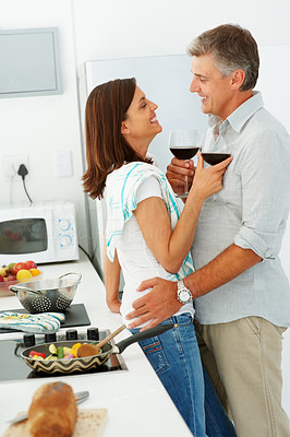 Happy mature couple drinking wine together in the kitchen