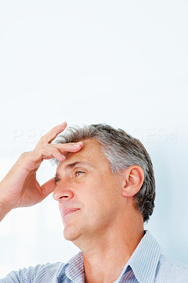 Closeup of a tensed mature man having a headache over a white background