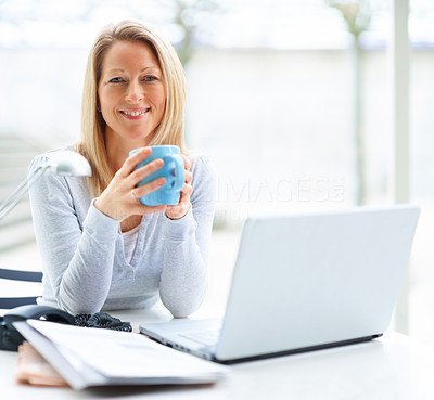 Portrait of mature business woman with a laptop and drinking coffee