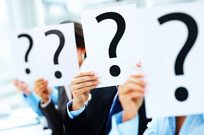 Closeup of colleagues holding question mark on boards in the conference room