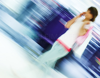 Blur motion image of a female carrying shopping bags while speaking on the mobile
