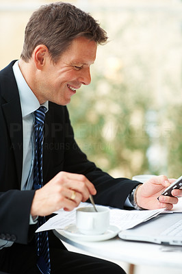 Portrait of successful business man using mobile phone and having tea