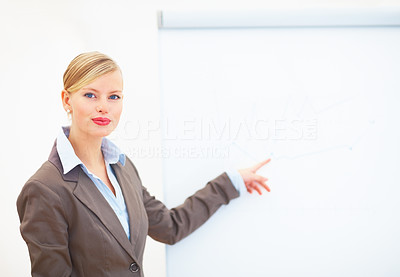 Portrait of confident young businesswoman pointing at blank board