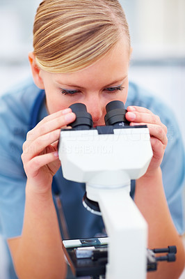 Portrait of young female doctor viewing through microscope