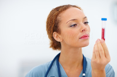 A young female health professional looking at a blood sample