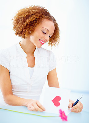 Beautiful smiling woman writing on valentines card