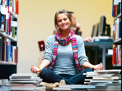 Young girl meditating with books around her in the library