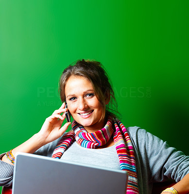 Pretty smiling young woman using a cellphone and laptop on green