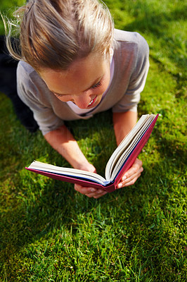 Portrait of cute female reading a book on grass