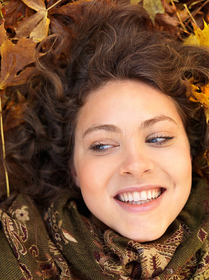 Closeup of a beautiful young woman lying on maple leaves