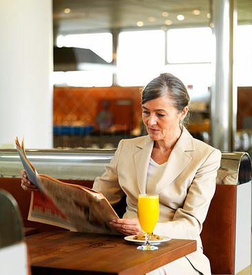 Older woman reading newspaper in a cafe