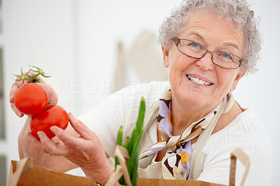 Closeup of an old woman smiling and holding tomatoes