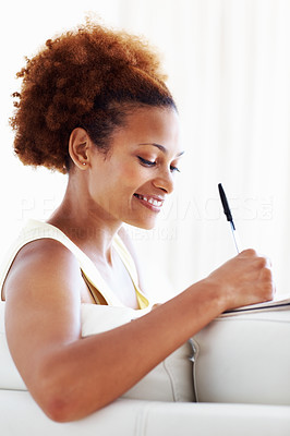 Woman writing in diary on couch