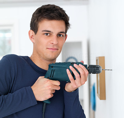 Closeup of a young man drilling a hole in wall