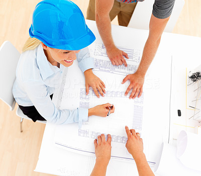 Top view of female architect with colleagues working on blue prints