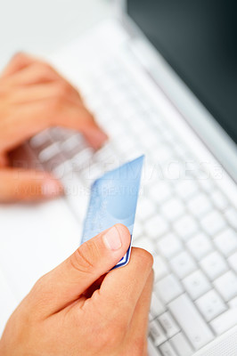 Hands holding credit card by a laptop keyboard