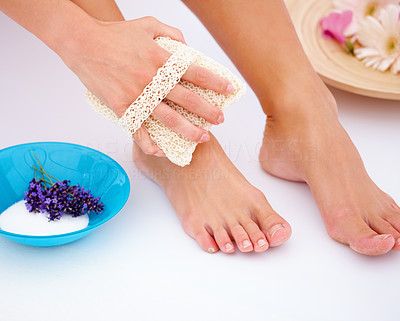 Closeup of a young woman using bathing sponge on legs isolated on white