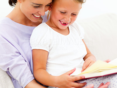 Young mother sitting with her daughter and reading book