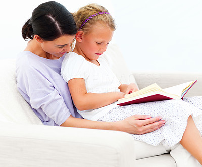 Mother and daughter sitting on couch and reading book