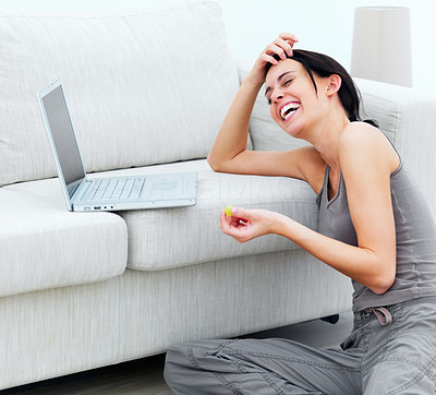 Closeup of a laughing young lady sitting on floor with laptop on sofa