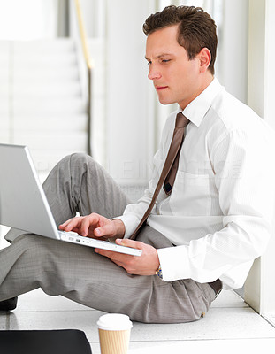 Successful handsome business man sitting on floor and working on his computer