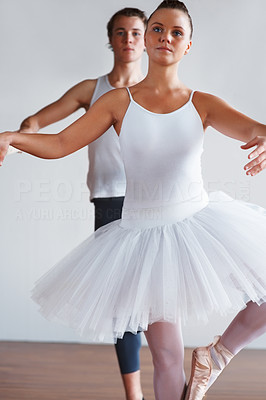 Ballerina dancing by a ballet bar with trainer in background