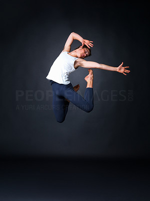 Male ballet dancer jumping high against black background