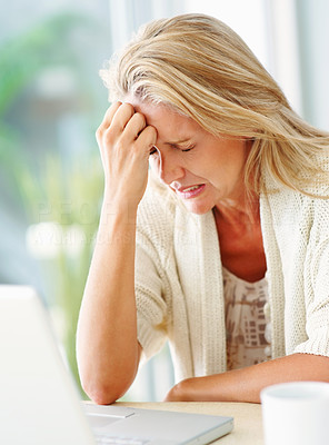 Mature woman with worried expressing in front of laptop