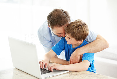 Happy young father hugging his son working on laptop