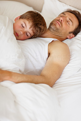 Small boy sleeping over his father