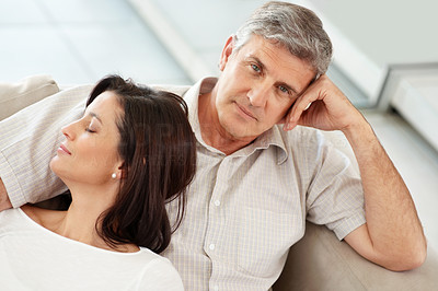 Mature man sitting with his wife sleeping on couch