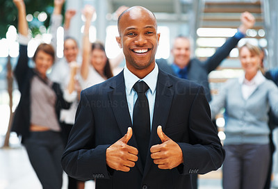 Businessman giving his approval with excited colleagues in background