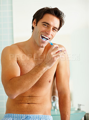 Happy shirtless guy brushing his teeth at the bathroom