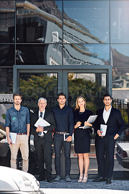 Buy stock photo Portrait of a team of focused professionals standing in front of a modern office building